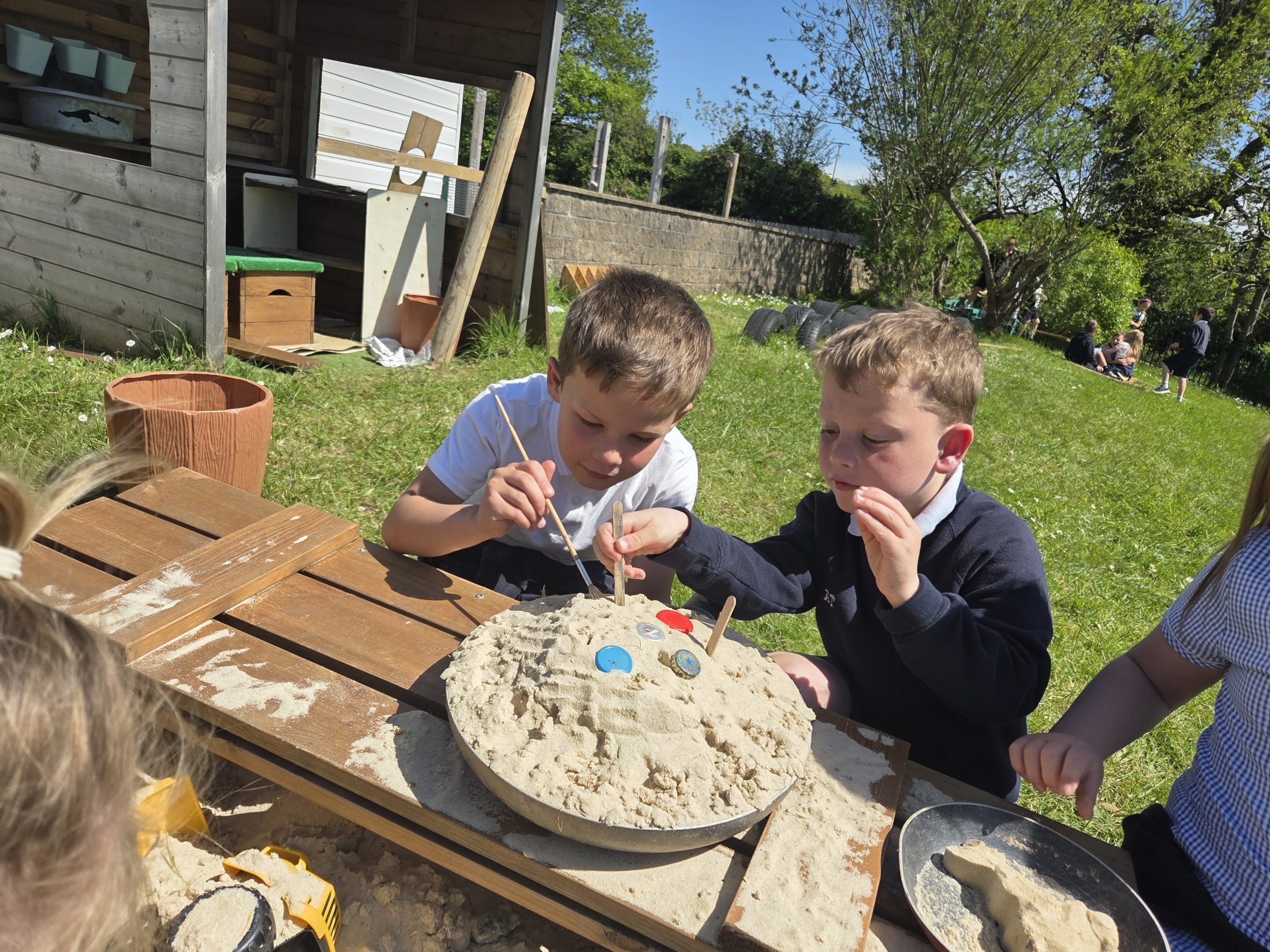 Pupils creating a sand activity outdoors