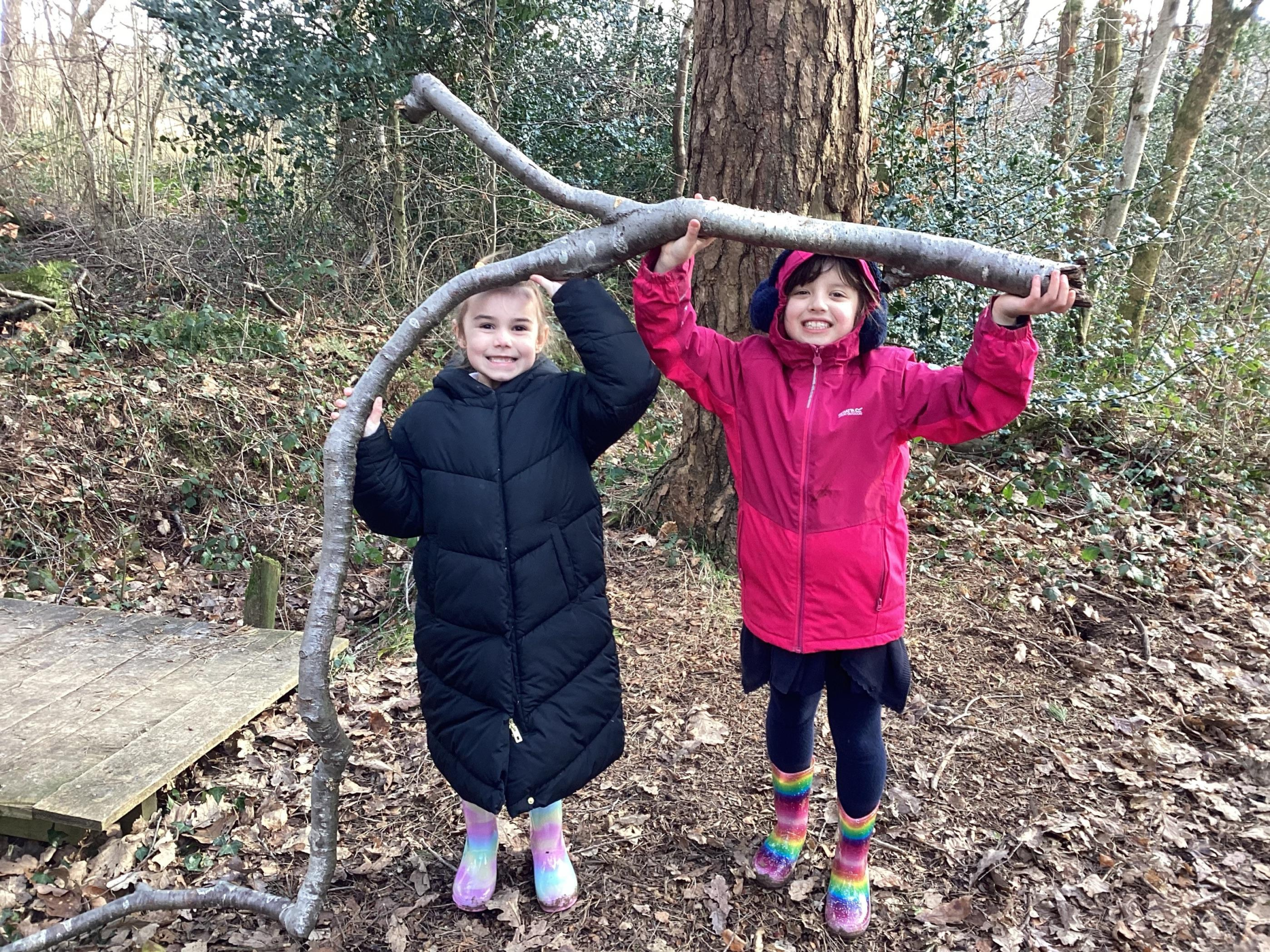 Pupils carrying a branch together in the woodland