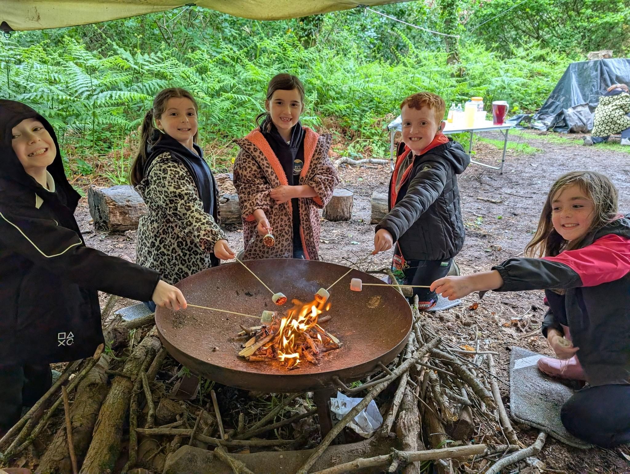 Children toasting marshmallows together around an outdoor fire